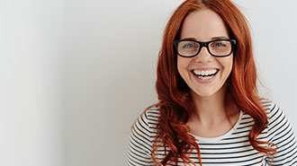 jüngerer Frau mit langen, roten Haaren, Brille und weiss/schwarzem Streifen-T-Shirt